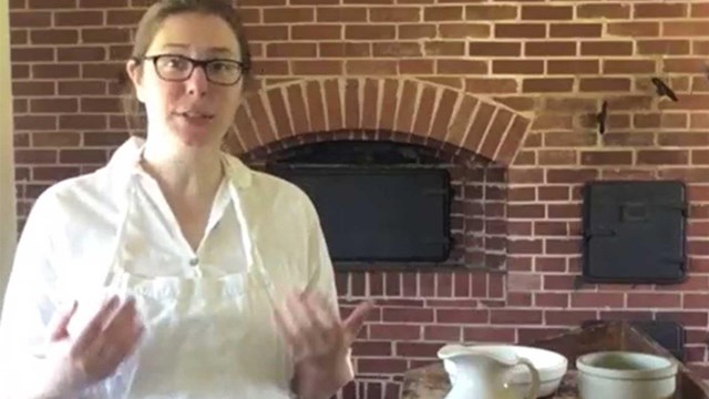 Woman in white clothing  in front of a brick fireplace